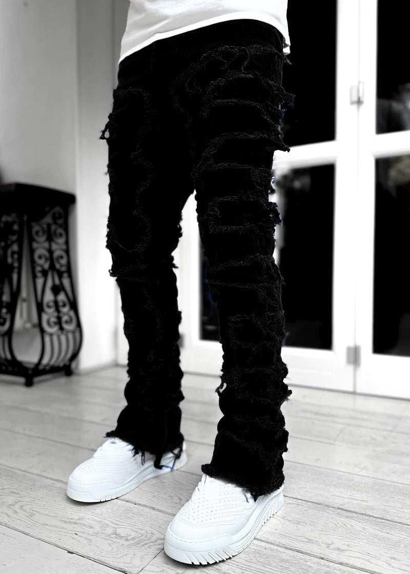 Black distressed skinny jeans with frayed texture and slim fit, paired with white sneakers