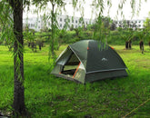 Dark green waterproof dome tent with orange accents set up on grassy lawn outdoors