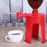 Red plastic beverage dispenser stand pouring drink into white cup on wooden surface