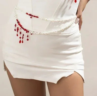 White bodycon mini skirt with pearl and red bead chain detail, fitted style, split hem