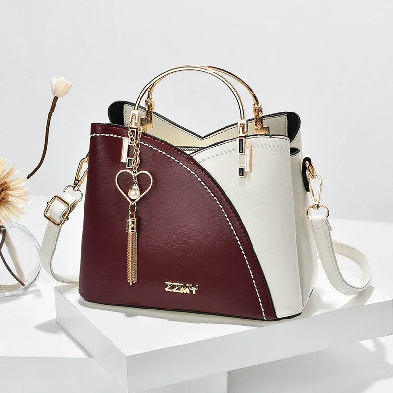 Elegant two-tone handbag in burgundy and cream faux leather with gold hardware, structured fit