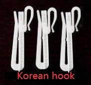 Three white plastic cloth hooks with a simple, modern design on a dark background.