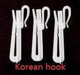 Three white plastic cloth hooks with a simple, modern design on a dark background.
