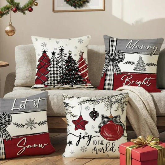 Set of decorative Christmas throw pillow covers with red, black, and white festive designs on a beige sofa, featuring plaid patterns, holiday trees, snowflakes, and ornament graphics.