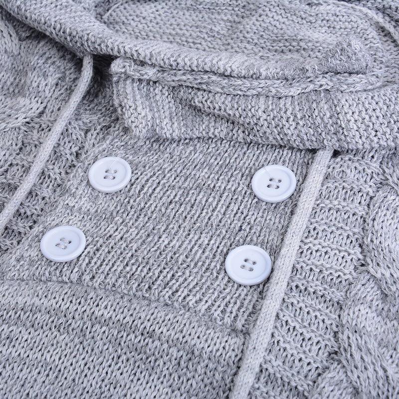 Close-up of light gray knit sweater with white buttons and textured cable pattern