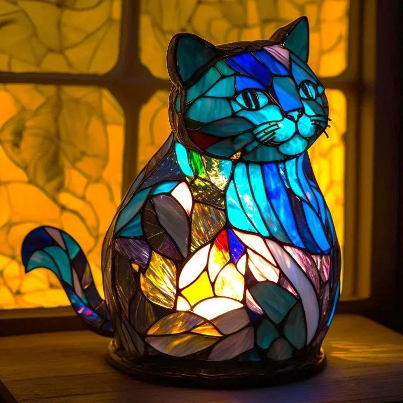 Colorful stained glass cat lamp with blue, teal, and yellow glass, glowing warmly indoors.