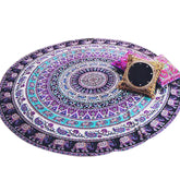 Colorful round mandala tapestry rug with vibrant bohemian patterns and decorative accent pillows