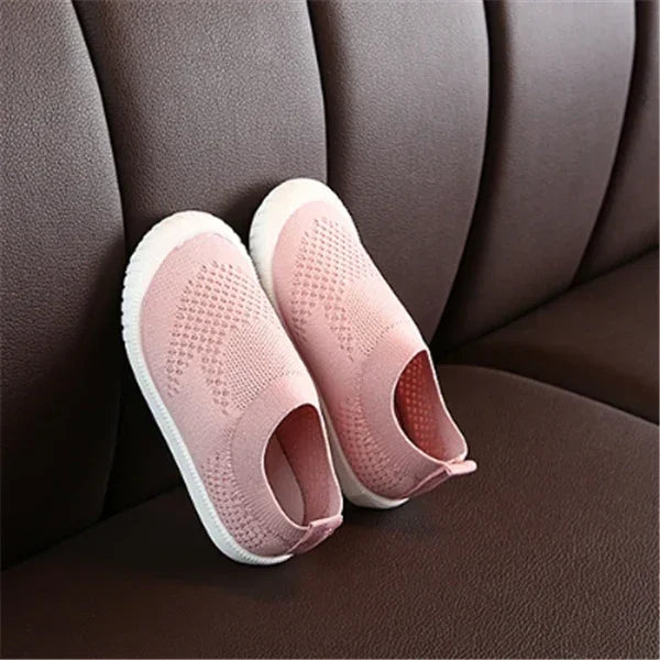 Pink slip-on knit sneakers with white soles, lightweight and breathable fit, on brown seat