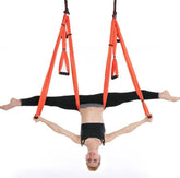 Woman in black athletic wear performing splits on orange aerial yoga hammock