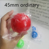 Hand holding a red rubber ball in clear packaging, 45mm size, with blue and green balls in background