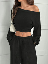 Woman wearing a black off-shoulder cropped sweatshirt and matching drawstring joggers set
