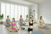 Women in colorful sports bras and shorts practicing yoga in a bright, modern studio