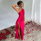 Woman wearing a vibrant pink satin one-shoulder dress with high slit, slim fit, elegant style.
