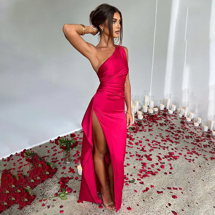 Woman wearing a vibrant pink satin one-shoulder dress with high slit, slim fit, elegant style.