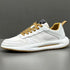 White low-top sneaker with textured leather panels, mesh sides, and tan laces on grey background
