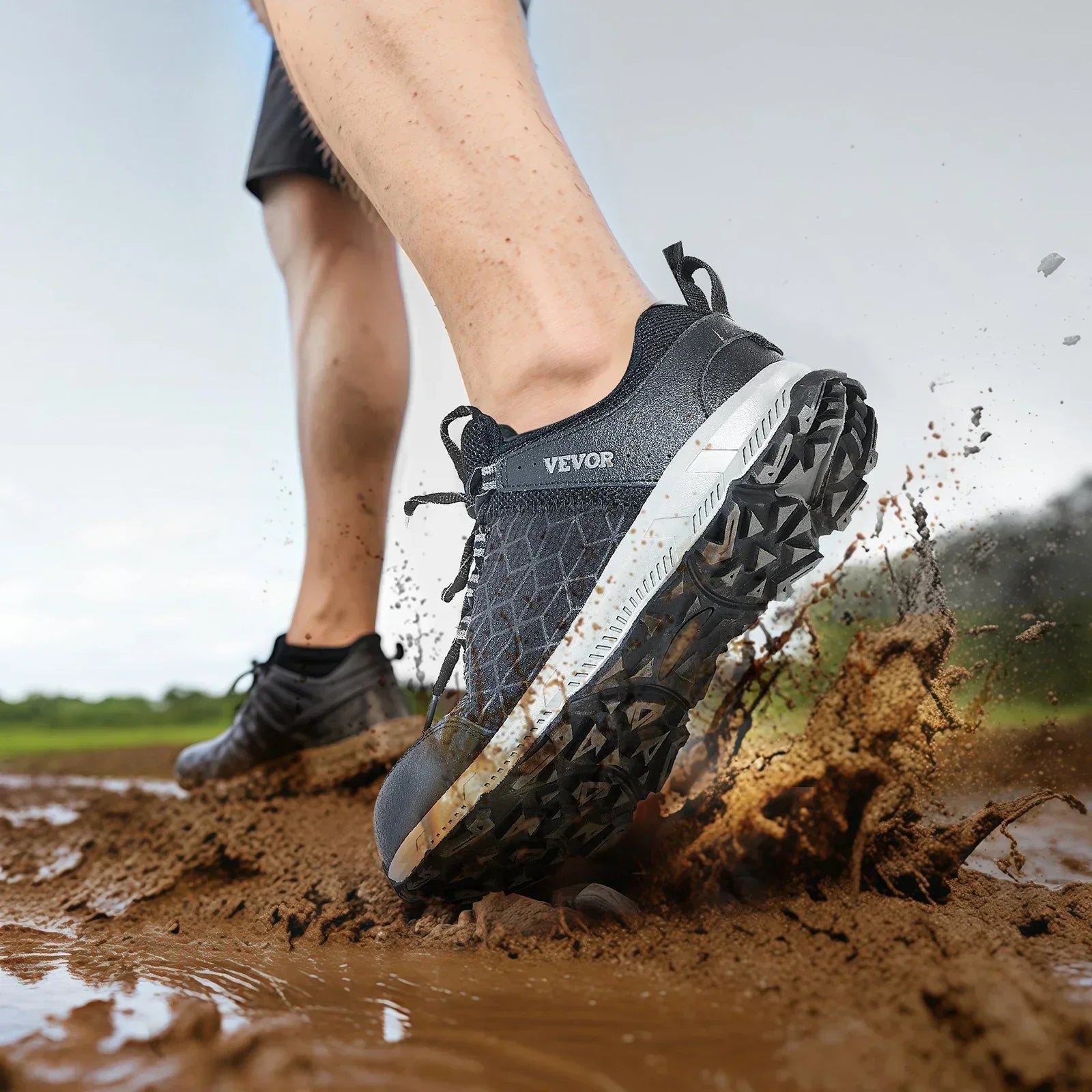 Black athletic sneakers with textured soles, worn outdoors in muddy terrain, active fit