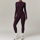 Woman wearing fitted long sleeve dark purple jumpsuit with front zipper, athletic style