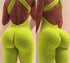 Back view of a woman wearing a neon yellow textured jumpsuit with criss-cross open back and body-hugging fit.