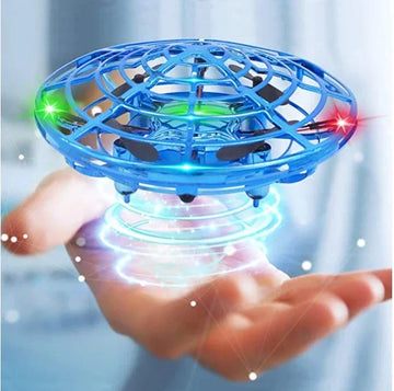 Blue futuristic toy drone with LED lights hovering above an open hand indoors.