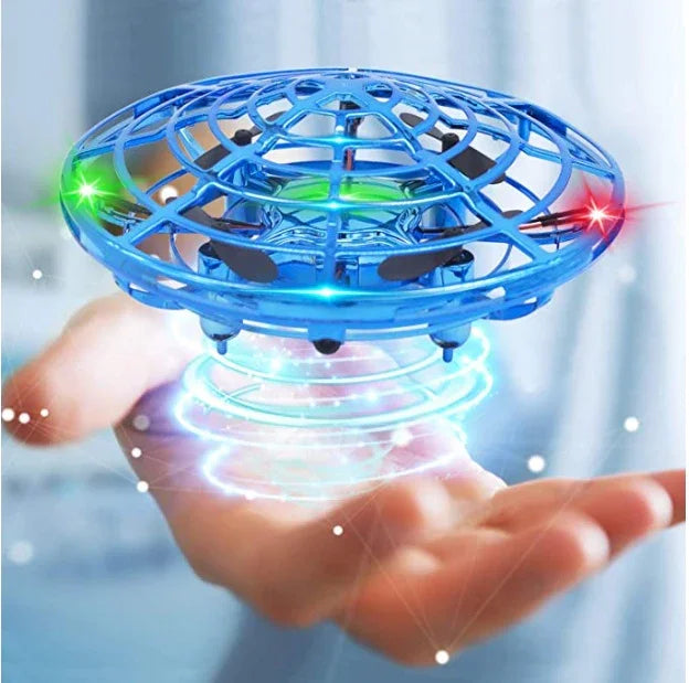 Blue futuristic toy drone with LED lights hovering above an open hand indoors.