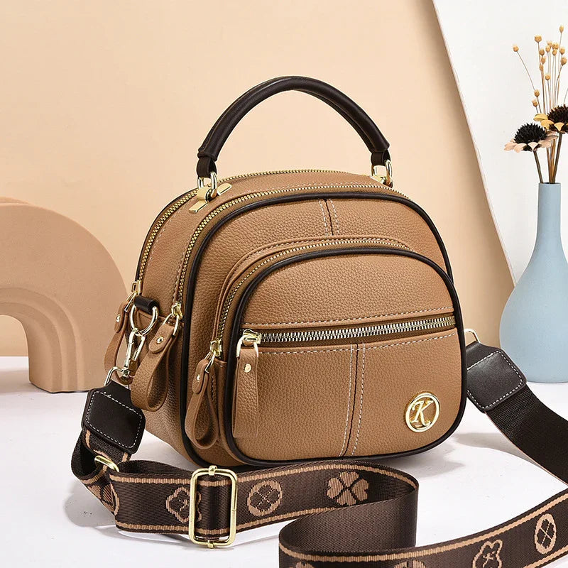 Brown leather crossbody bag with gold hardware, adjustable strap, and multiple zip pockets