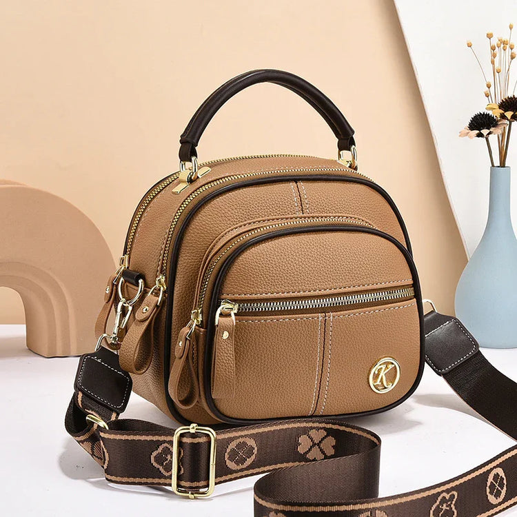 Brown leather crossbody bag with gold hardware, adjustable strap, and multiple zip pockets