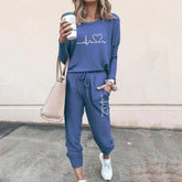 Woman in blue jogger set with heart graphic, relaxed fit, holding coffee, casual streetwear