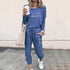 Woman in blue jogger set with heart graphic, relaxed fit, holding coffee, casual streetwear