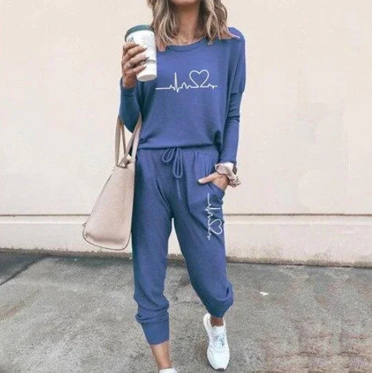 Woman in blue jogger set with heart graphic, relaxed fit, holding coffee, casual streetwear