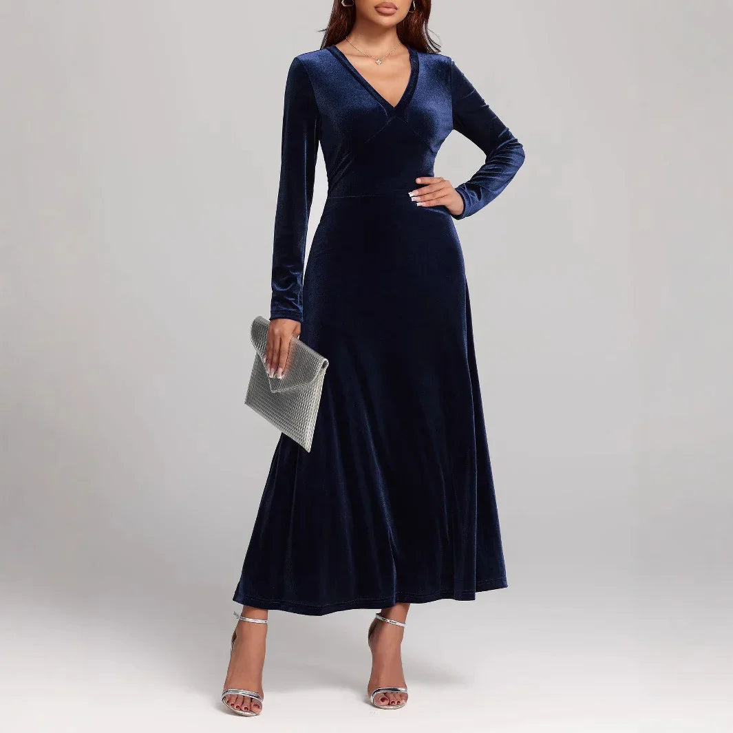 Woman wearing a navy blue velvet long-sleeve maxi dress with a V-neck and fitted waist.