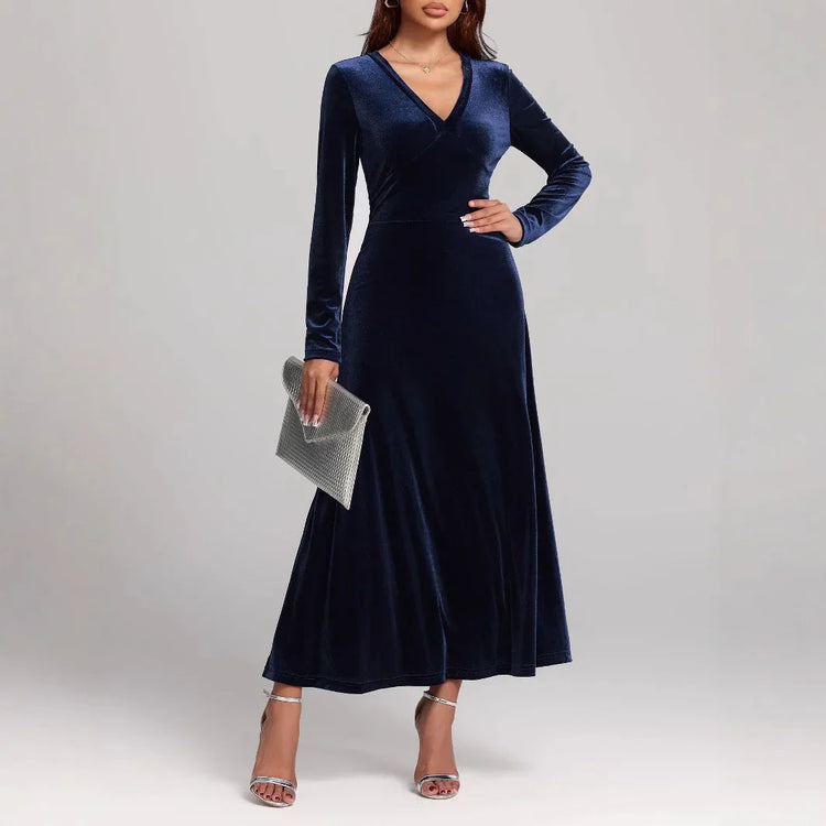 Woman wearing a navy blue velvet long-sleeve maxi dress with a V-neck and fitted waist.