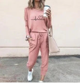 Woman in pink casual loungewear set with graphic top and jogger pants, holding coffee
