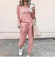 Woman in pink casual loungewear set with graphic top and jogger pants, holding coffee