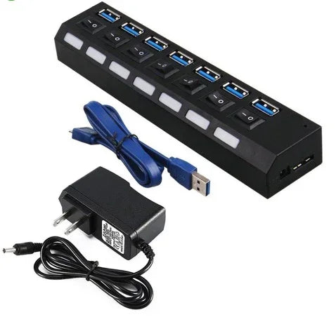 Black USB hub with seven ports, individual switches, USB cable, and power adapter
