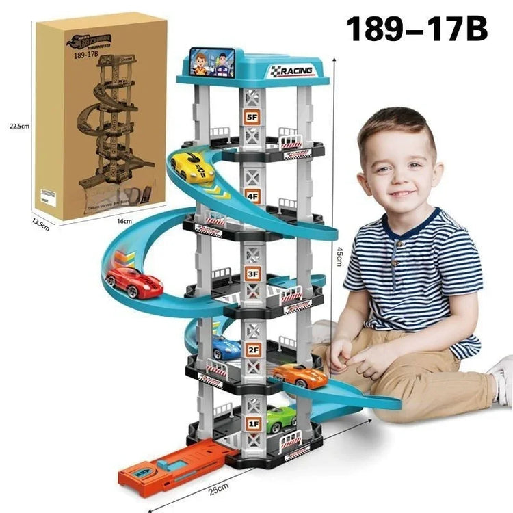 Child in striped t-shirt and tan pants sitting beside multi-level toy car racetrack.
