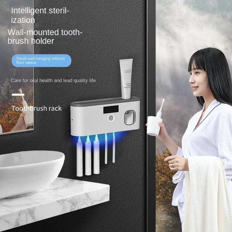 Woman in white robe holding towel near modern wall-mounted sterilizing toothbrush holder in bathroom.