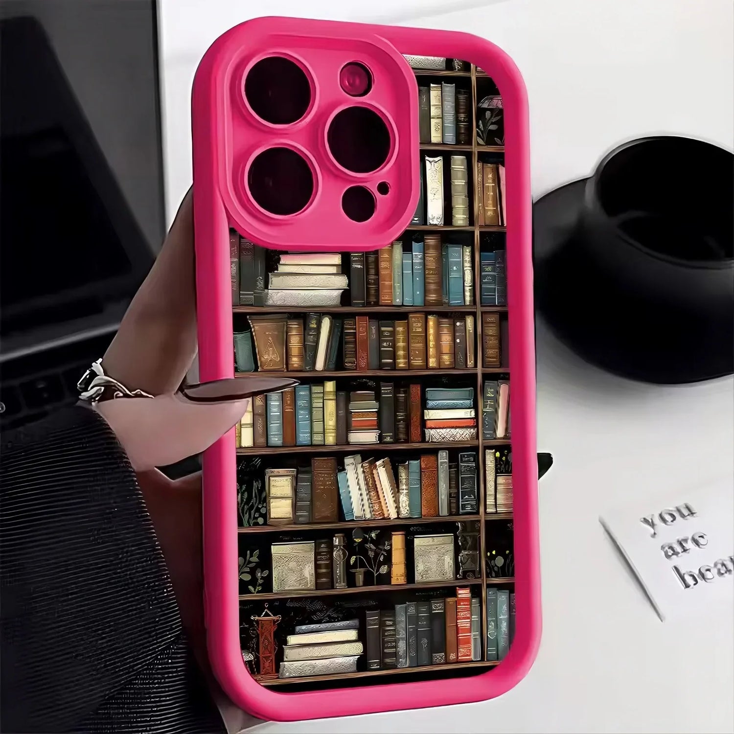Pink phone case with bookshelf print, protective design, fits snugly, modern street style