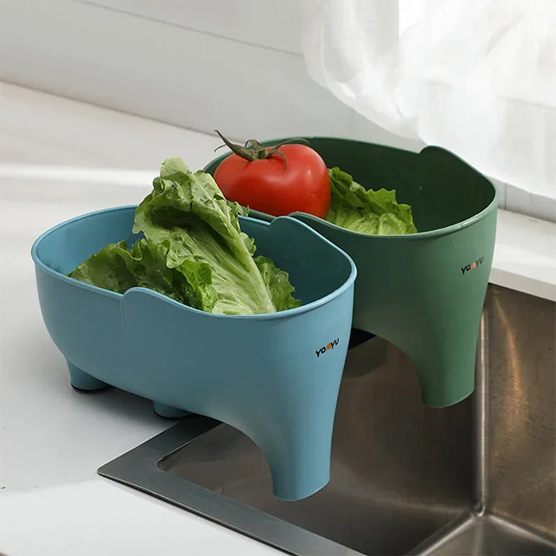 Plastic sink colanders in blue and green holding fresh lettuce and tomato, kitchen setting