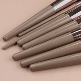 Close-up of taupe synthetic makeup brush handles with metallic accents on beige background