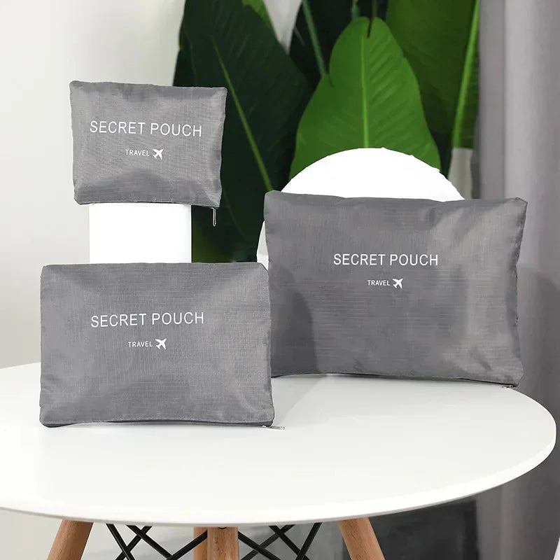 Set of three gray nylon travel pouches with zippers on a white table, minimalist style