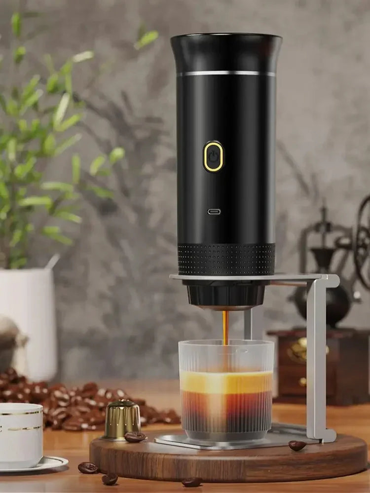 Sleek black portable espresso maker brewing coffee into a glass cup on a wooden tray indoors.