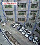 Modern building exterior with large windows, blue accents, and parked cars beside it.