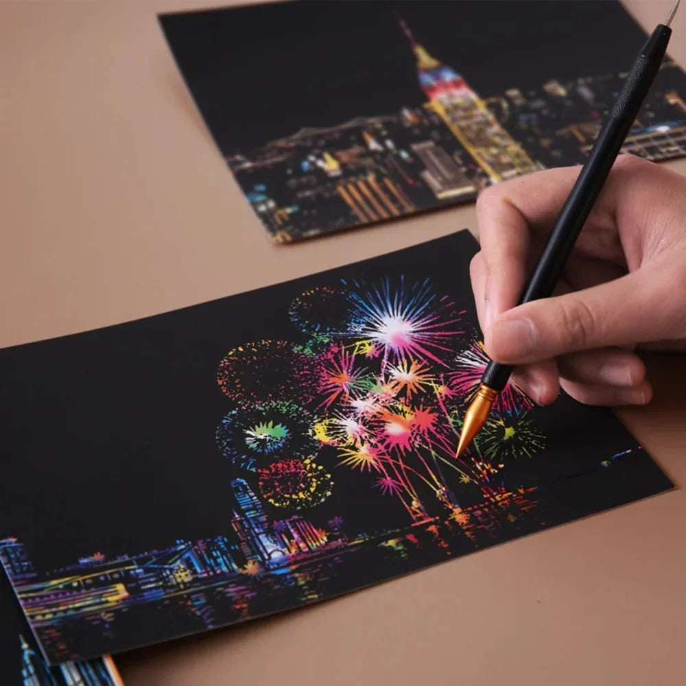 Hand using a stylus to scratch off a colorful fireworks cityscape on black paper