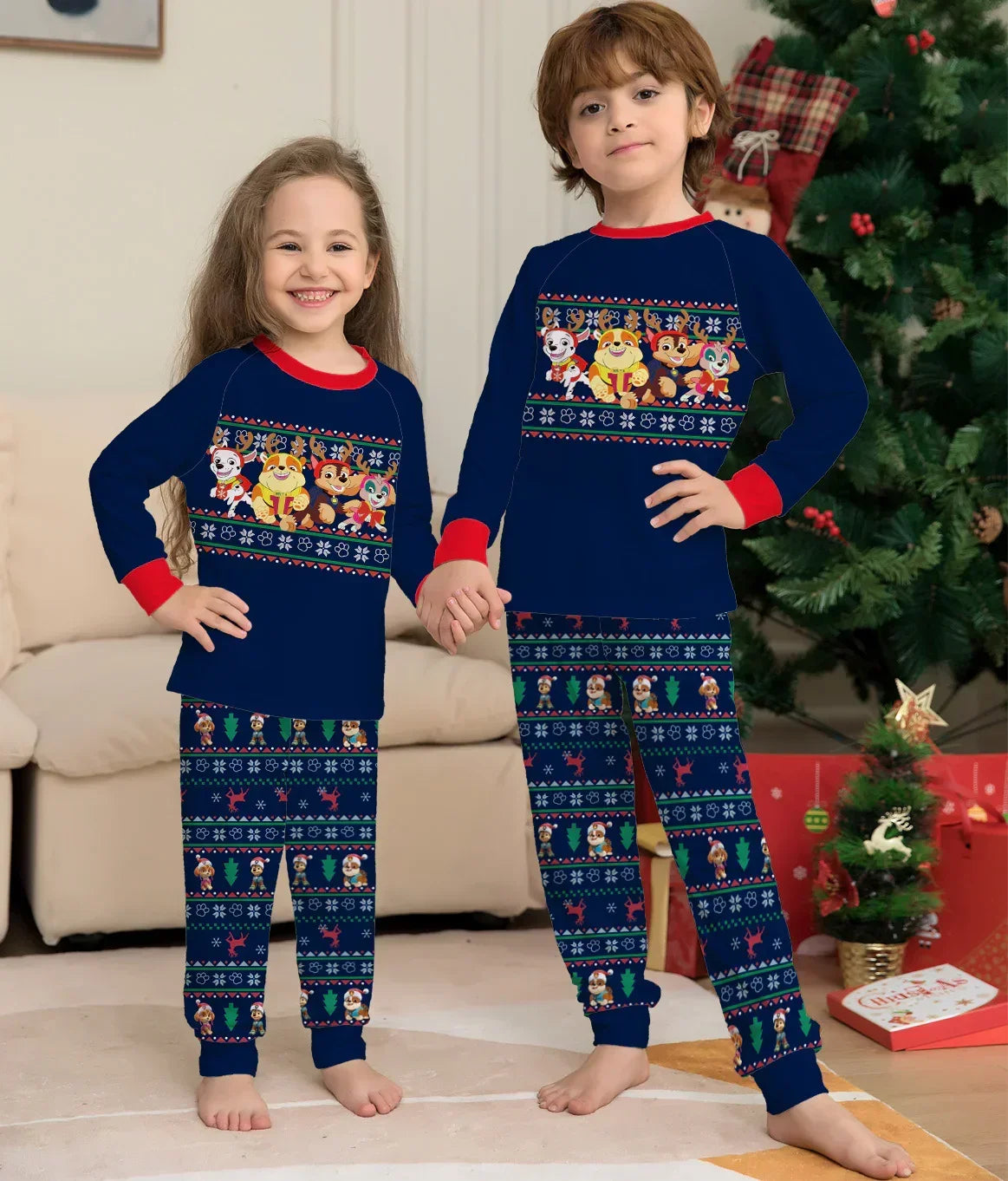 Kids wearing matching navy blue cartoon print holiday pajamas with red cuffs, relaxed fit.