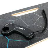 Black wireless remote control on a textured electric skateboard deck with geometric design