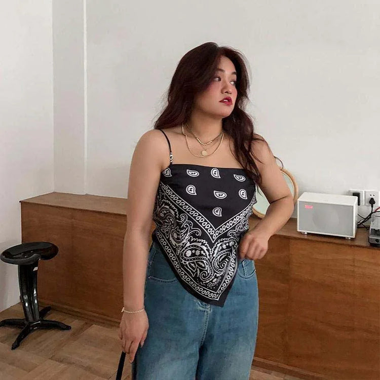 Woman wearing black paisley bandana crop top with spaghetti straps and relaxed blue jeans