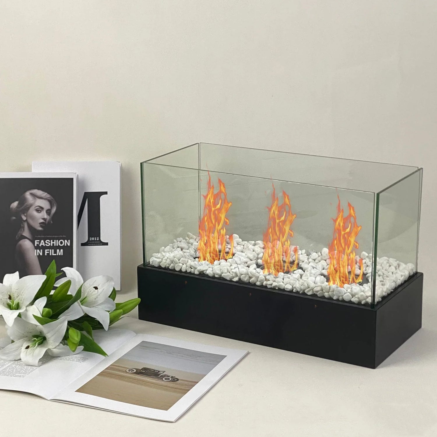 Rectangular glass tabletop fireplace with white stones and orange flames, modern minimalist decor
