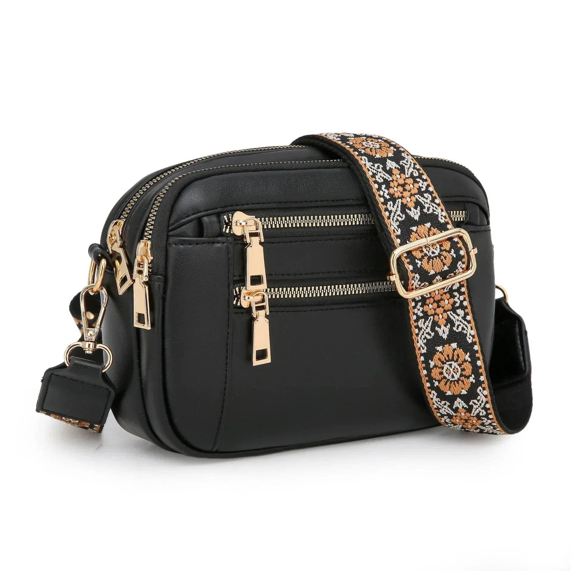 Black faux leather crossbody bag with gold zippers and floral patterned adjustable strap