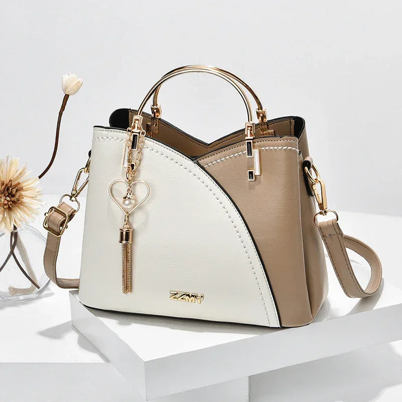 Chic two-tone beige and white faux leather handbag with gold metal handle and heart charm