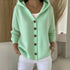 Woman wearing a mint green knit button-up hoodie with relaxed fit and white pants